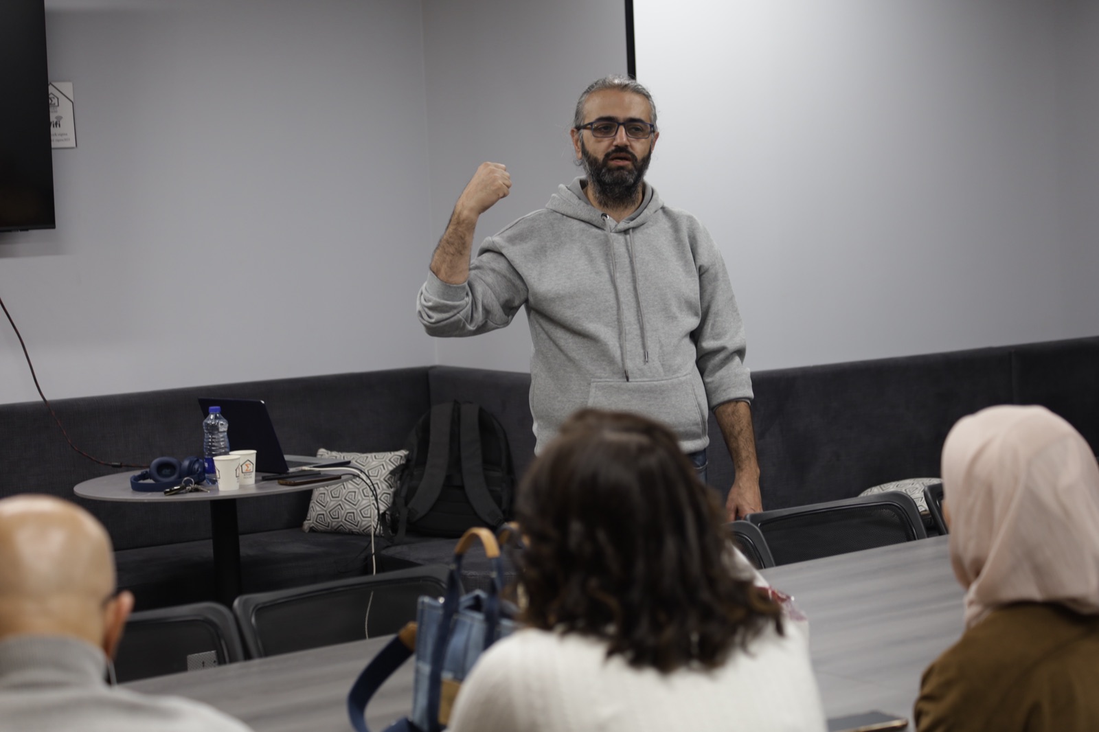 Sigma Study House session — Mousa Soutari mid-gesture presenting on AI usage, audience in foreground, Amman, March 2026.